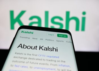 Mobile phone with website of US prediction market company Kalshi Inc. on screen in front of logo. Focus on top-left of phone display.