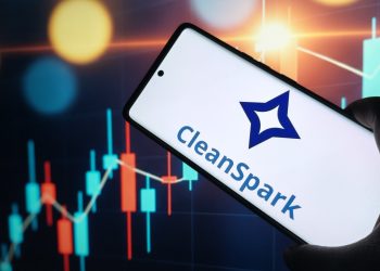 CleanSpark logo on smartphone screen with stock market chart background