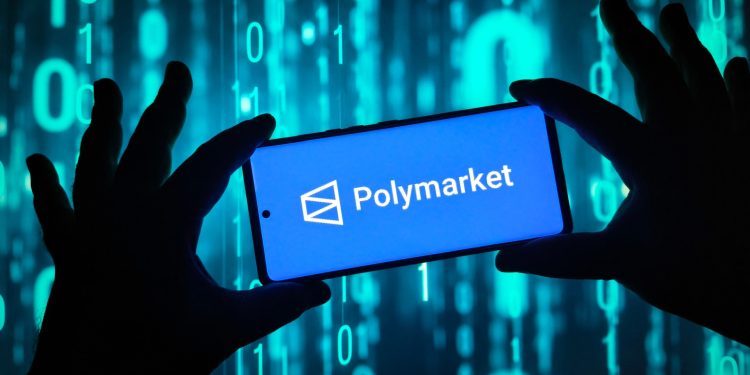 Hands holding smartphone with Polymarket logo on screen
