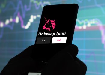An investor's analyzing the uniswap (uni) coin on screen. A phone shows the ETF's prices to invest