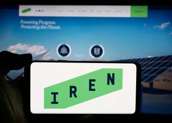 Person holding cellphone with logo of Australian Bitcoin mining company Iris Energy Ltd. (IREN) in front of webpage. Focus on phone display.