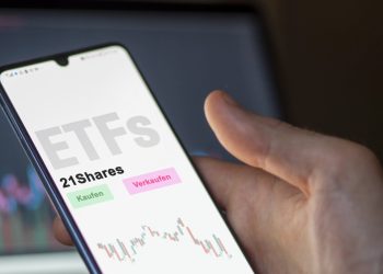 An investor's analyzing the 21Shares etf fund on screen. A phone shows the ETF's prices food commodities to invest. German text.