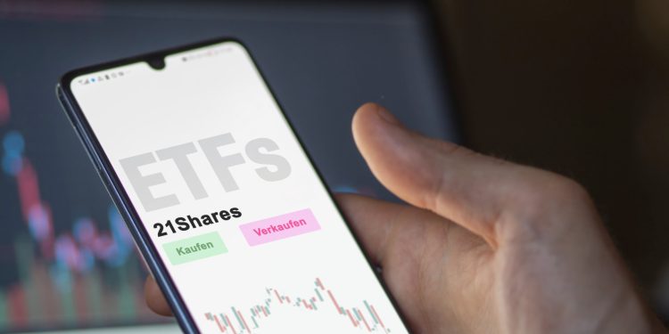 An investor's analyzing the 21Shares etf fund on screen. A phone shows the ETF's prices food commodities to invest. German text.