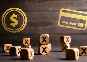 Numerous wooden blocks marked with "X" are scattered, while a dollar coin and credit card float above.