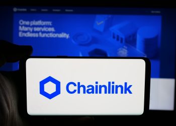 Stuttgart, Germany - 12-16-2025: Person holding cellphone with logo of blockchain oracle network Chainlink on screen in front of webpage. Focus on phone display.