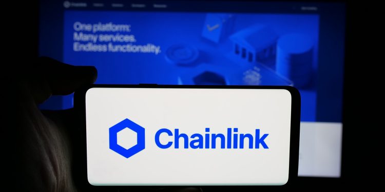 Stuttgart, Germany - 12-16-2025: Person holding cellphone with logo of blockchain oracle network Chainlink on screen in front of webpage. Focus on phone display.