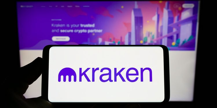 Stuttgart, Germany - 09-26-2022: Person holding mobile phone with logo of American crypto company Payward Inc. (Kraken) on screen in front of web page. Focus on phone display.
